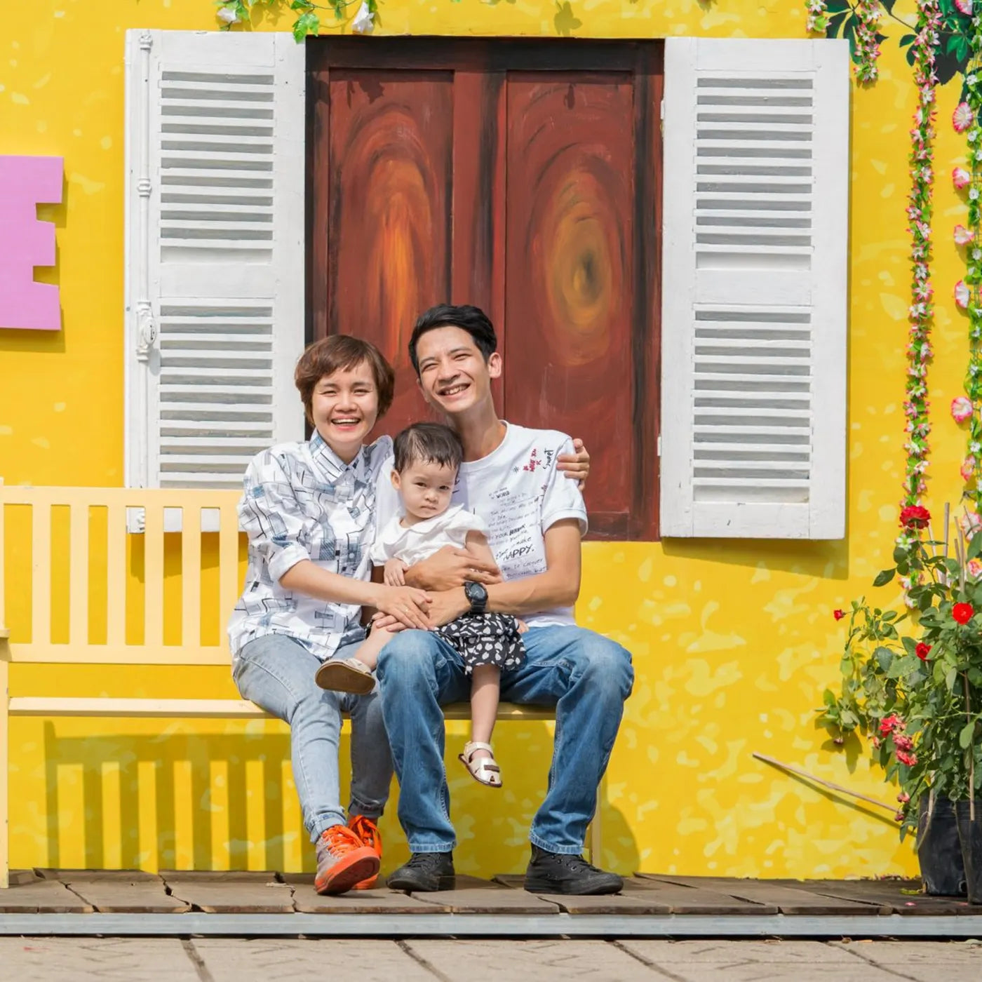 Familia sonriendo frente a una pared amarilla